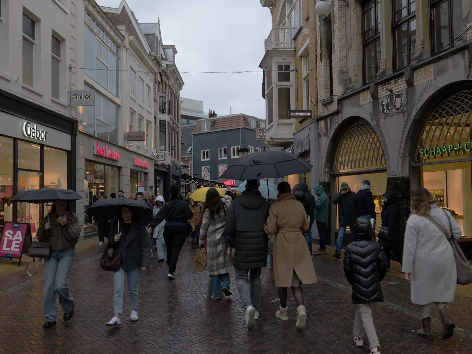 Shoppers with umbrellas on a rainy pedestrian street