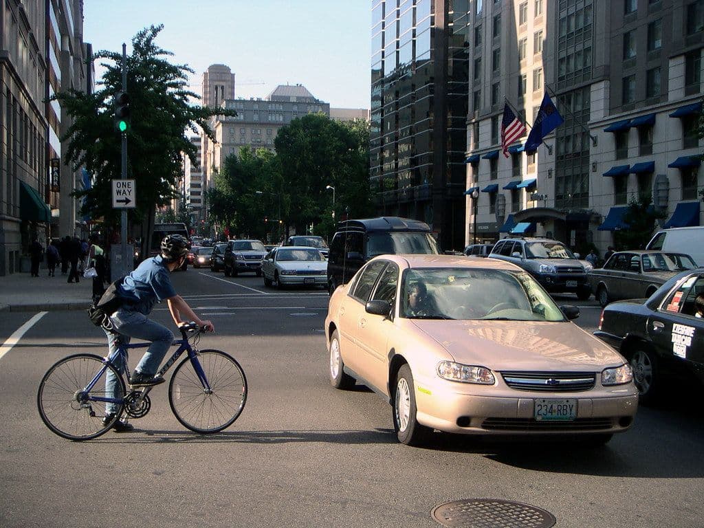 Cyclist riding next to a car on a city street