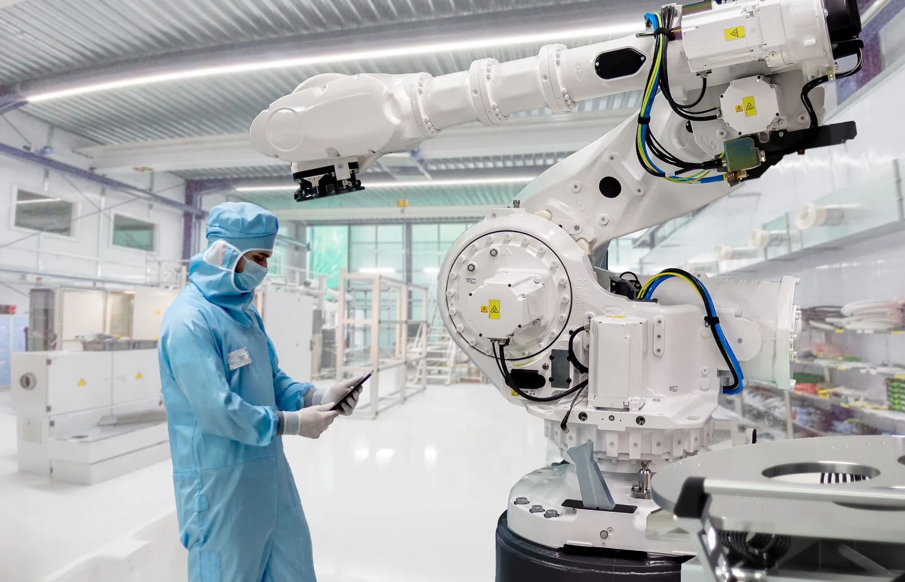 Industrial robot arm next to an operator in a cleanroom